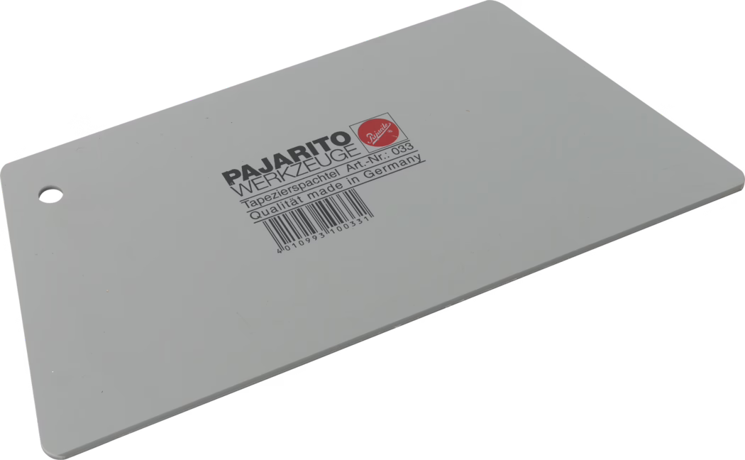 Grijze rechthoekige plastic behangspatel, diagonaal liggend op een witte achtergrond, afgeronde hoeken en een ophangoog aan één korte zijde. Zwart opdruk in het midden 'PAJARITO WERKZEUGE' met vermelding 'Tapezierspachtel Art.-Nr.: 033 Qualität made in Germany' en daaronder een streepjescode. Glad, vlak blad voor het gladstrijken van behang en het verdelen van lijm.