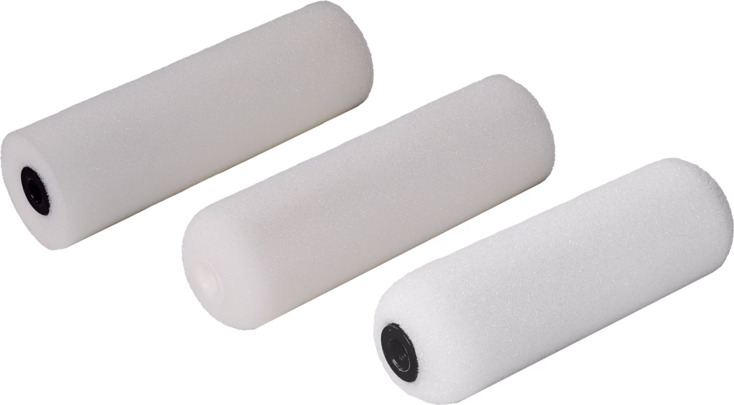 Pajarito_Dummy_Small roller Foam Easy Line_168967_168968_168969_168970_2021-11 Drie witte schuimverfrollers diagonaal gerangschikt op een witte achtergrond. Elke roller is cilindrisch met een fijne open-cel schuimstructuur; twee hebben zwarte kunststof uiteinden en één heeft een wit uiteinde. De rollers zijn vrijstaand gefotografeerd en geschikt voor kleine verf- en afwerkingsklussen; zacht, gelijkmatig licht benadrukt het poreuze oppervlak, de fijne textuur en subtiele schaduwen.