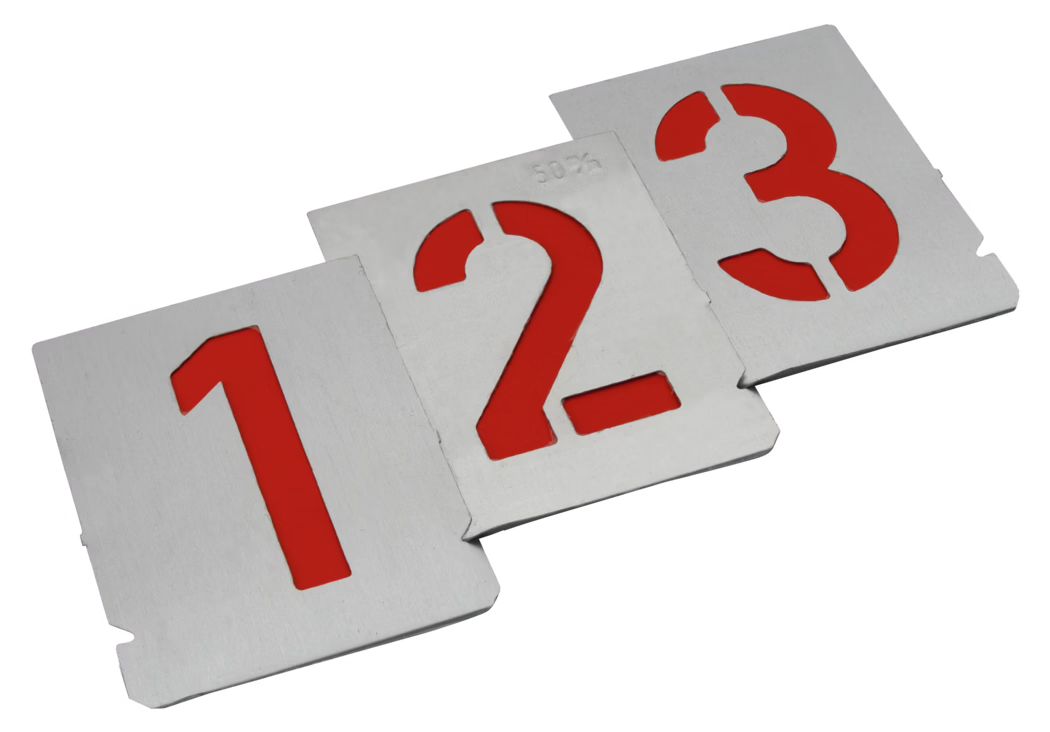 Three rectangular metal stencil plates with the numerals '1', '2' and '3' cut out, revealing a vivid red backing beneath each cutout. The silver-coloured plates are arranged diagonally from the lower-left foreground to the upper-right background and overlap slightly. The metal surfaces show a fine brushed texture and cleanly punched edges; small alignment notches are visible along the plate borders. The digits are crisply and geometrically formed, creating a strong contrast between the matte metal and the bright red fill. Even studio lighting produces soft shadows and subtle highlights; the background is plain white. The composition emphasises the numeric sequence and the industrial, utilitarian character of the stencils, which appear sturdy and suitable for painting or marking surfaces.