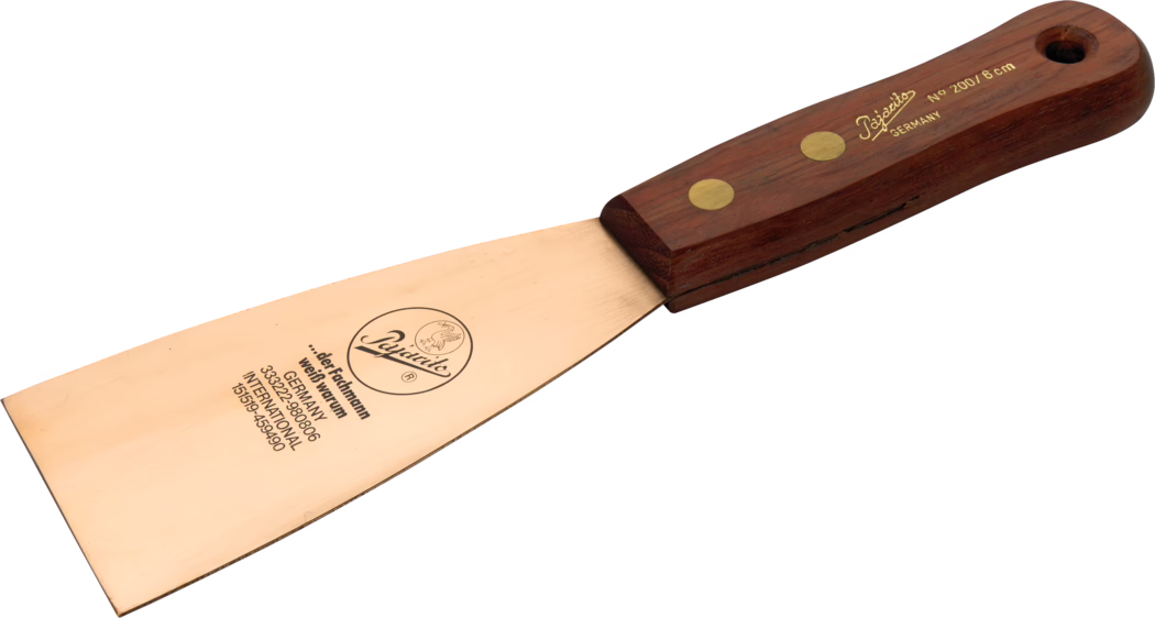 Pajarito_Dummy_Beryllium spatula wood handle_012868_012869_012870_2021-02 Close-up van een handgereedschap: een schildersplamuurmes met een brede koperkleurige metalen plaat en een donkerhouten handvat met twee koperen klinknagels. Op het blad staat een merklogo en tekst, waaronder 'Germany' en de maat 'No 200 / 8 cm', met lichte krassen en een afgeschuinde rand. Het handvat is ergonomisch afgerond en heeft een ophanggat aan het uiteinde; het gereedschap is gefotografeerd tegen een witte achtergrond.