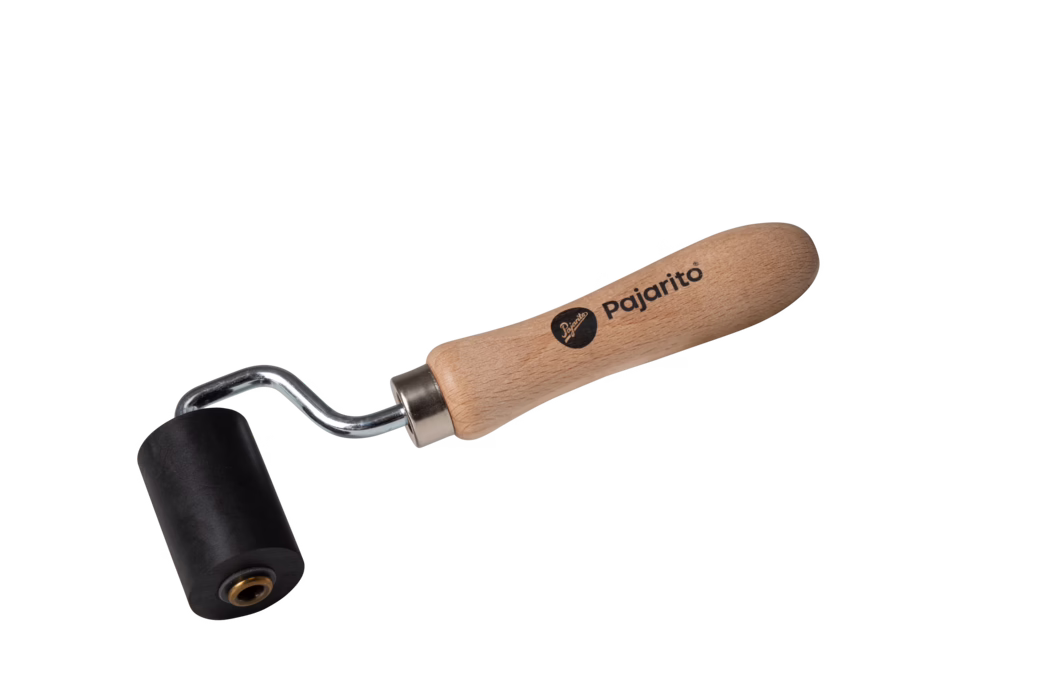 Pajarito_Dummy_Pressure roller hard rubber small_159651_2021-02 Een kleine handroller met een glad houten handvat met het opschrift "Pajarito", een verchroomde gebogen metalen as en een cilindrische zwarte rubberen roller. Het gereedschap is bedoeld om naden aan te drukken, lijmen en vinyl glad te strijken en luchtbellen te verwijderen bij het behangen, leggen van vloeren of knutselwerk. Gefotografeerd op een witte achtergrond, toont het houten handvat duidelijke houtnerf en verbindt een metalen kraag het handvat met de roller; handzaam formaat voor precies werk.