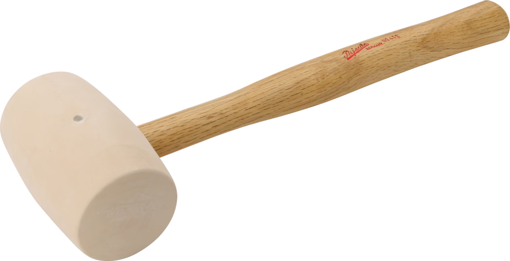 PAJARITO_Dummy_Rubber mallet _089408_2021-02 Close-up product photo of a wooden-handled mallet with a light beige, cylindrical rubber or rawhide head. The smooth, tapered oak handle shows visible wood grain and a small red printed brand marking near the top. The mallet is photographed against a clean white background, highlighting its simple workshop tool design and the smooth, slightly matte surface of the head.