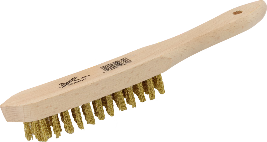 Pajarito_Dummy_Brass wire brush_034752_034753_034754_034755_014380_2021-02 Handige staalborstel met een glad, licht houten handvat en een rij verdraaide, messingkleurige metalen haren. Het langwerpige houten blok loopt over in een afgerond ergonomisch handvat met een ophanggaatje aan het uiteinde. Op de bovenzijde van het handvat is een gedrukt merklogo en een streepjescode zichtbaar. De metalen haren zijn gerangschikt in meerdere korte bosjes, gekreukt en licht onregelmatig aan de uiteinden, en geschikt voor zwaar schoonmaakwerk en het verwijderen van roest, verf of vuil van metalen oppervlakken. Het hout heeft een natuurlijke, onbehandelde uitstraling met zichtbare nerven. De borstel is op een witte achtergrond in lichte schuine aanzicht gefotografeerd.