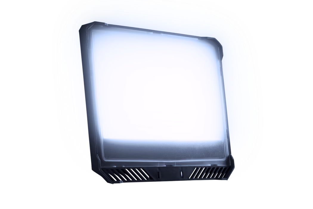Pajarito_Dummy_FlatLight Led Spotlight_179902_2024-07 Een licht gekanteld rechthoekig LED-paneel met een donkere kunststof rand en een matte diffuser die koel wit-blauw licht uitstraalt; de onderkant heeft schuine ventilatiesleuven en bevestigingsinkepingen. Het armatuur is los op een witte achtergrond geplaatst en vertoont subtiele reflecties en een zachte lichtgloed.