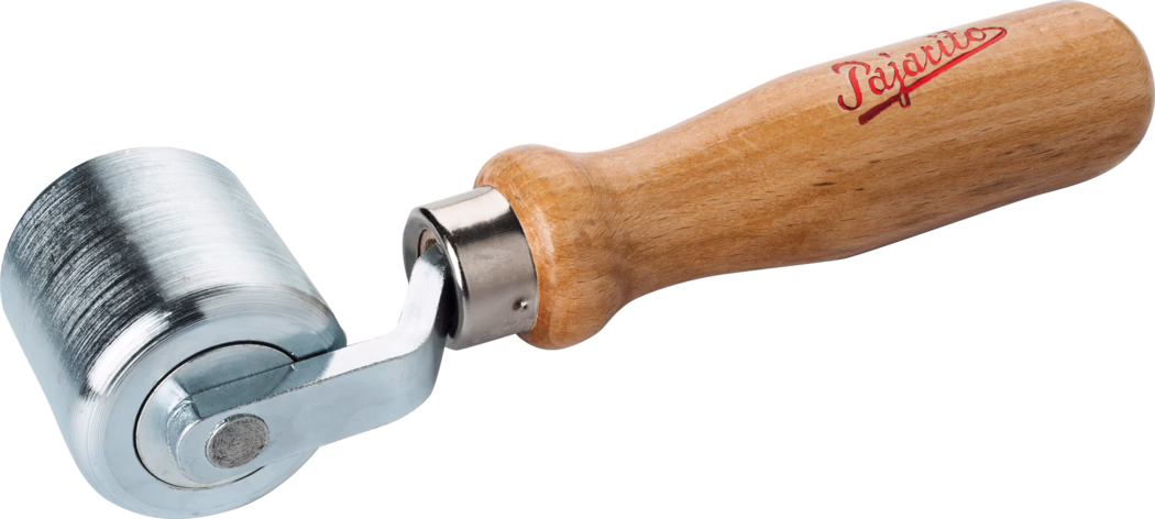 Pajarito_Dummy_Pressure roller steel_034611_2021-02 Close-up of a handheld seam roller with a short, cylindrical metal roller and a turned light-brown wooden handle. The roller is made of polished, slightly textured steel with faint machining marks; it is mounted on a small chromed metal yoke that pivots into a metal ferrule connecting to the handle. The wooden handle is varnished and ergonomically shaped with a rounded end; a red script logo is printed near the handle's top. The tool is photographed isolated on a white background with even lighting, showing surface details, reflections and the connection between roller and handle; it is typically used for pressing seams and smoothing materials such as wallpaper, vinyl or leather.